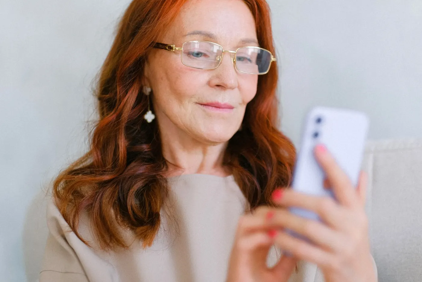 Una donna sorride guardando il telefono, a casa.